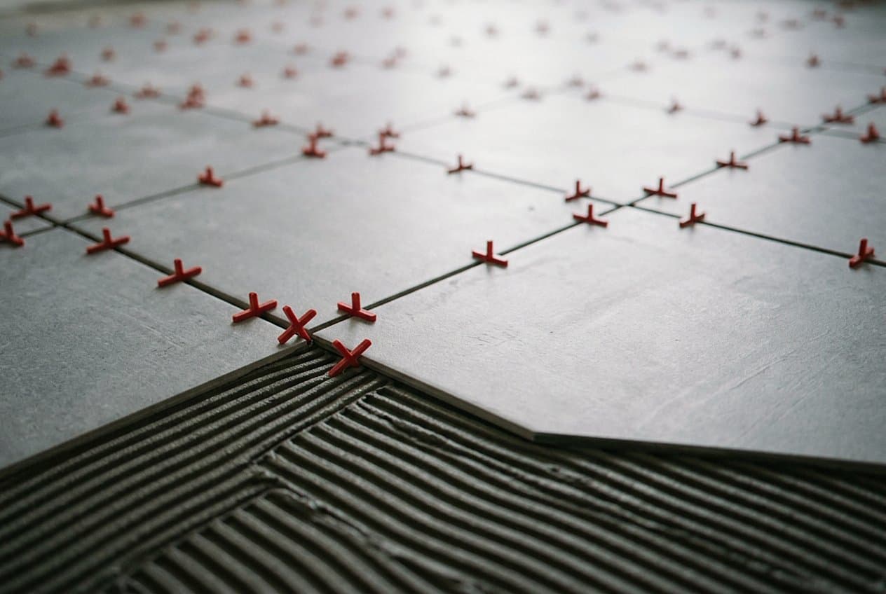 Red spacers on large tile set in mortar