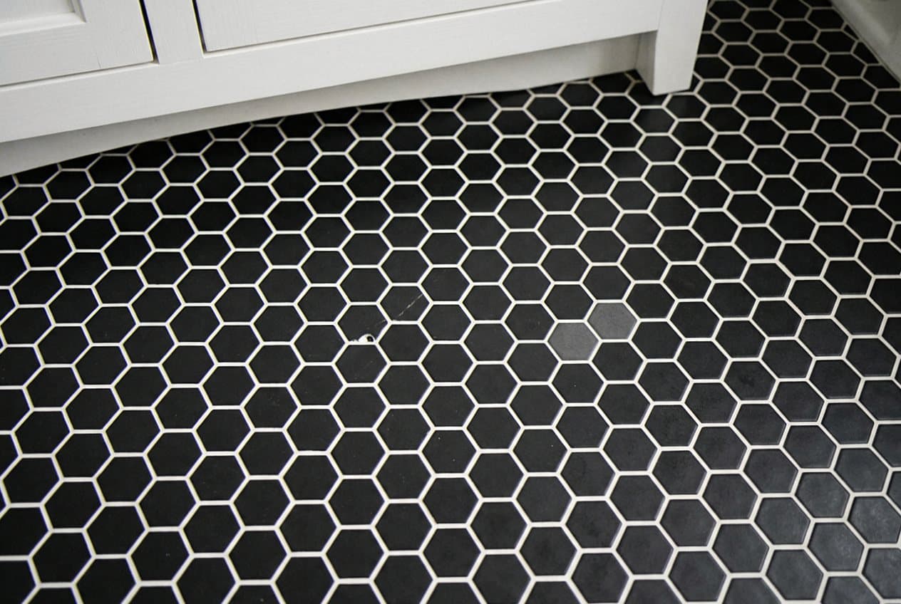 Black hexagon mosaic tile floor by a vanity