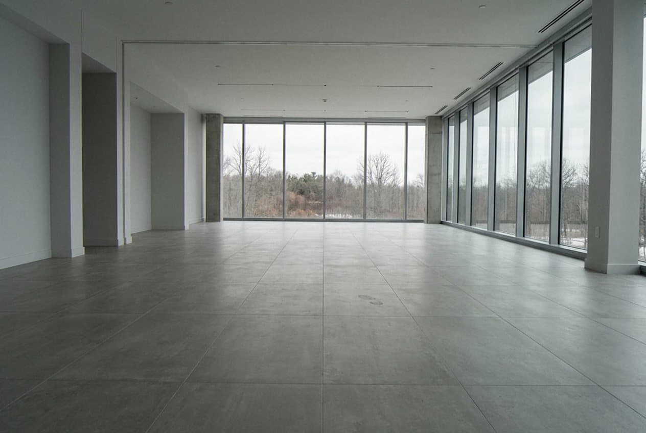 Large-format concrete-look tile floor beside floor-to-ceiling windows